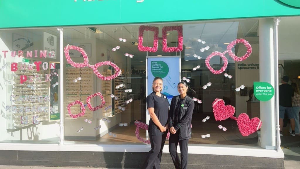 Leah Thomas and Zahra Jamil outside the pink-decorated Specsavers Burton store window